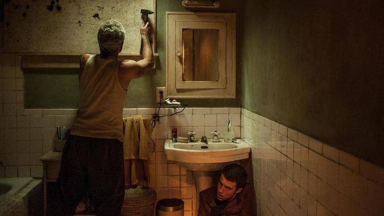 Escena de la película "No Respires": Stephen Lang es "El hombre ciego" que vemos con el martillo mientras Dylan Minnette es Alex y se esconde bajo el lavabo. 