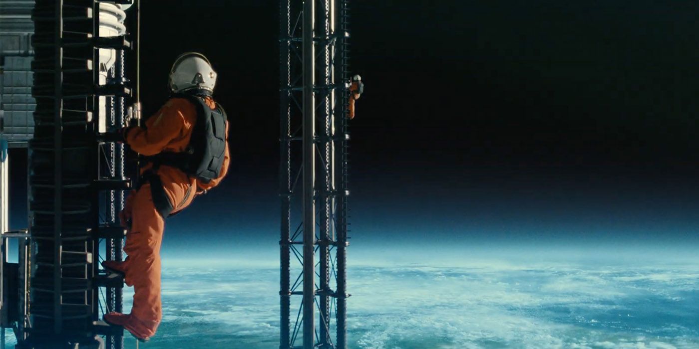 Dos astronautas aparecen en la imagen, ambos visten rojas de astronautas color naranja. Se encuentran fuera del globo terráqueo, por lo que se puede ver en la imagen, parecen estar en una infraestructura espacial, en ese momento se encuentran en una especie de escalera, debajo de ellos, a miles de kilómetros, la Tierra. 